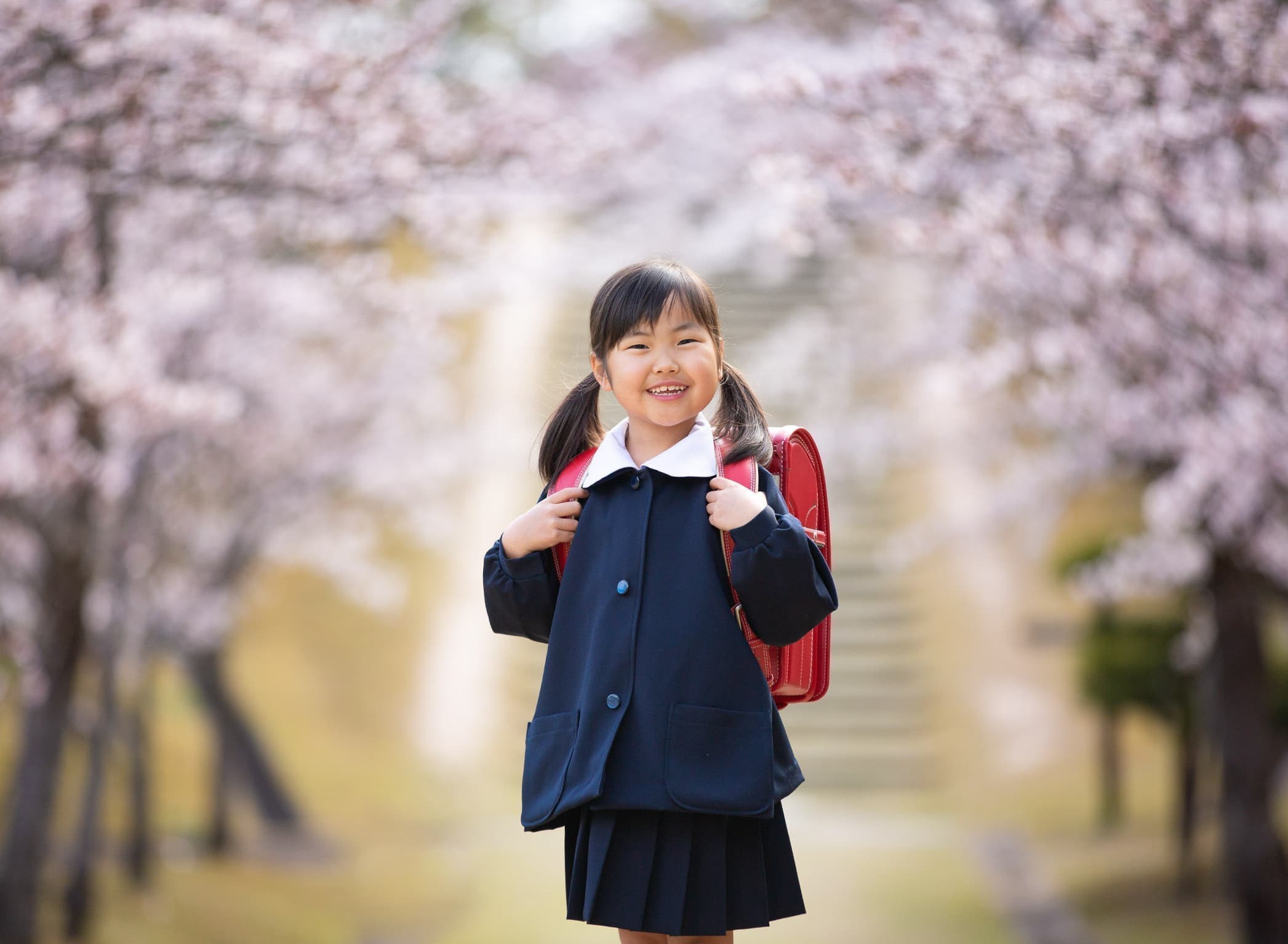 桜の木下でランドセルを持った女の子